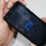 Manos sosteniendo un teléfono ZTE mostrando el logotipo de ZTE en la pantalla.