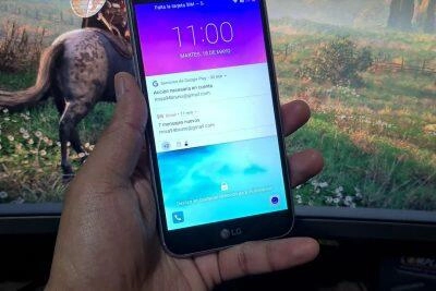 Mano sosteniendo el teléfono LG K10 bloqueado mostrando notificaciones. Desbloqueando el LG K10.