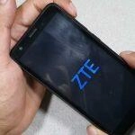 Manos sosteniendo un teléfono ZTE con el logotipo de ZTE en la pantalla. Desbloqueo del teléfono ZTE.