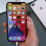 Mano sosteniendo un iPhone dorado mostrando aplicaciones.